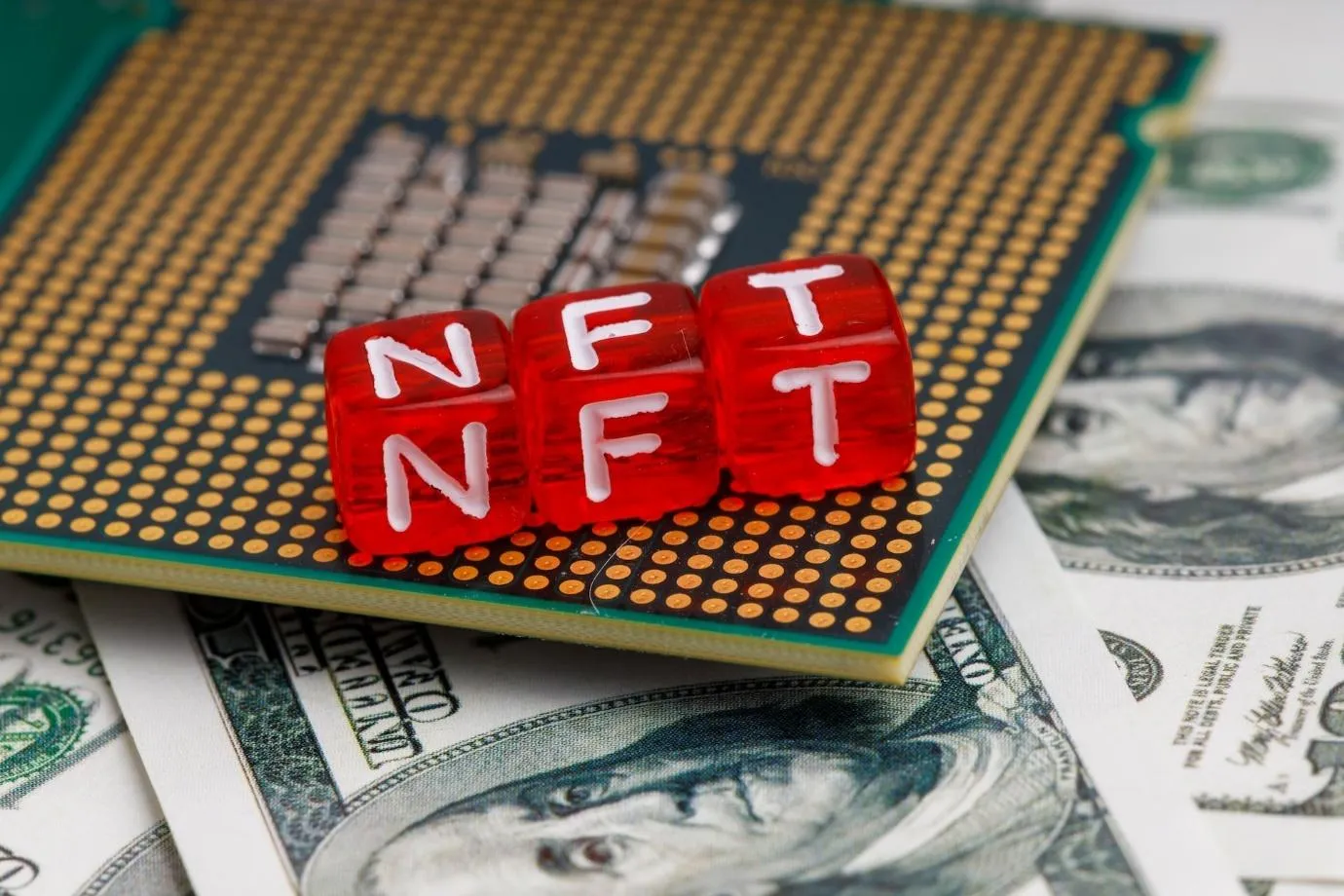 Letter cubes arranged to form an “NFT” over a microprocessor placed on top of money