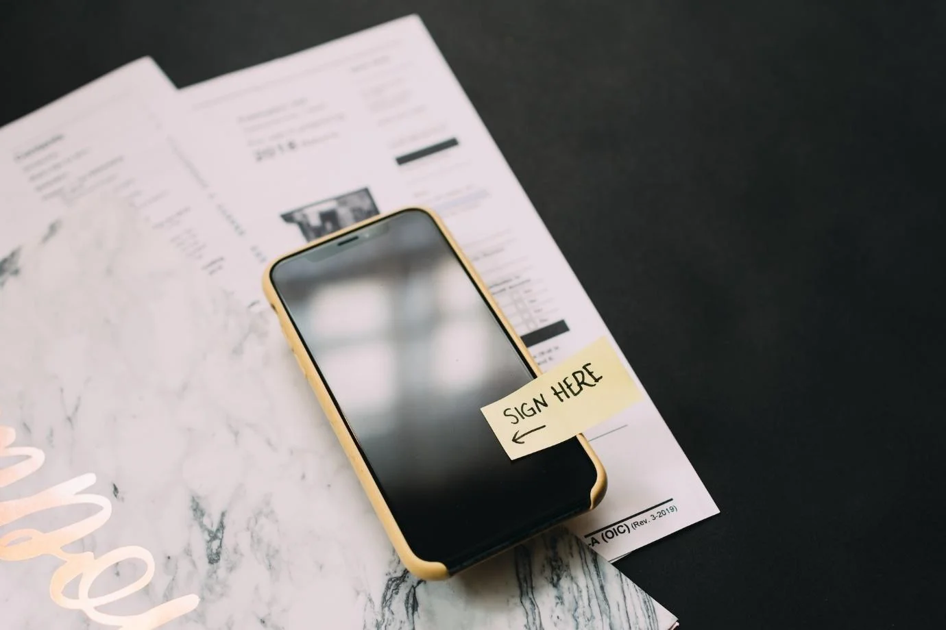 Smartphone with a sticky note with “Sign Here” written on it