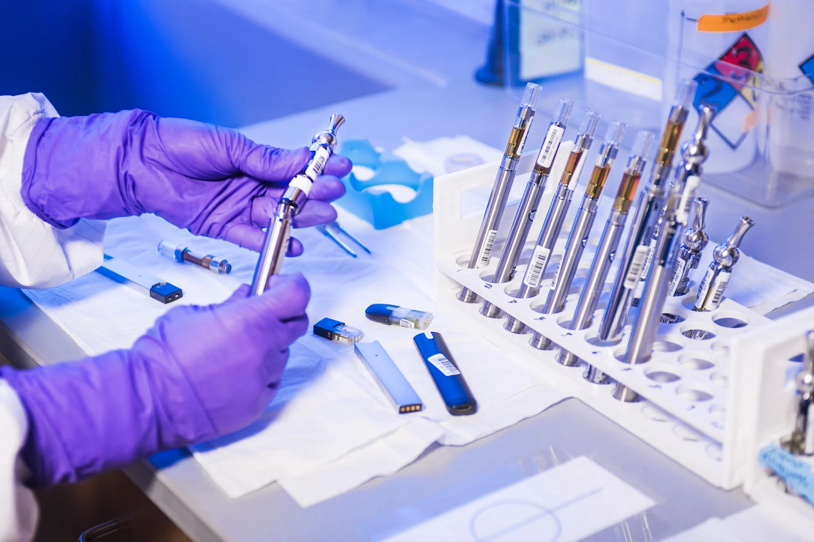 Gloved hands of a lab technician working with electronic cigarettes inside a lab.