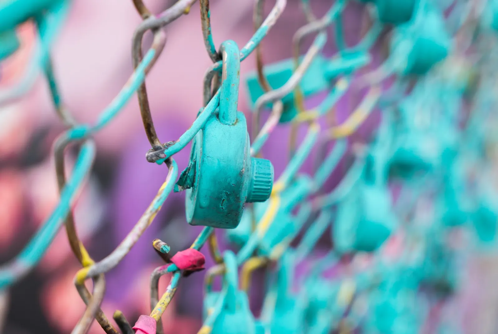 A lock on the fence with both colored aqua